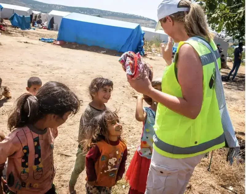 Aid worker standing with refugee children in an informal settlement in Turkey.